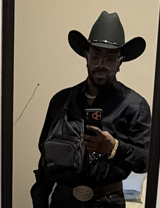 Napoleon B’Myte wearing a black cowboy hat, glasses, and a black shirt